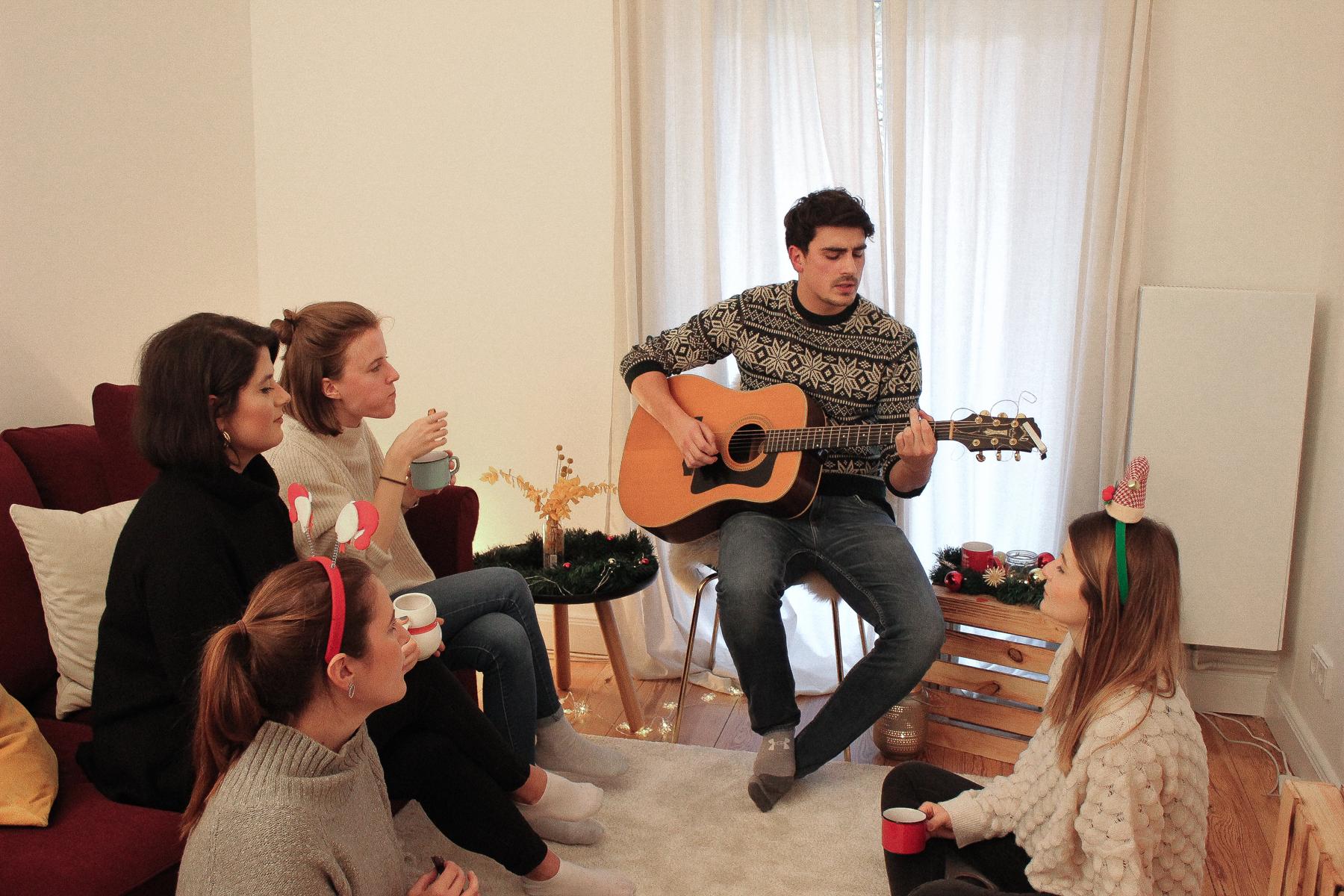 Sänger mit Gitarre singt Freunden Lieder zu Weihnachten